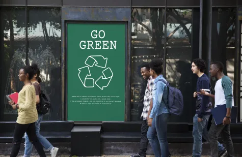 Straat met mensen waar een billboard staat met "go green"