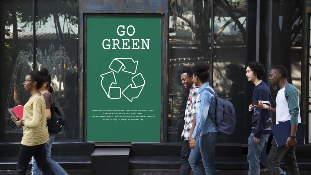 Straat met mensen waar een billboard staat met "go green"