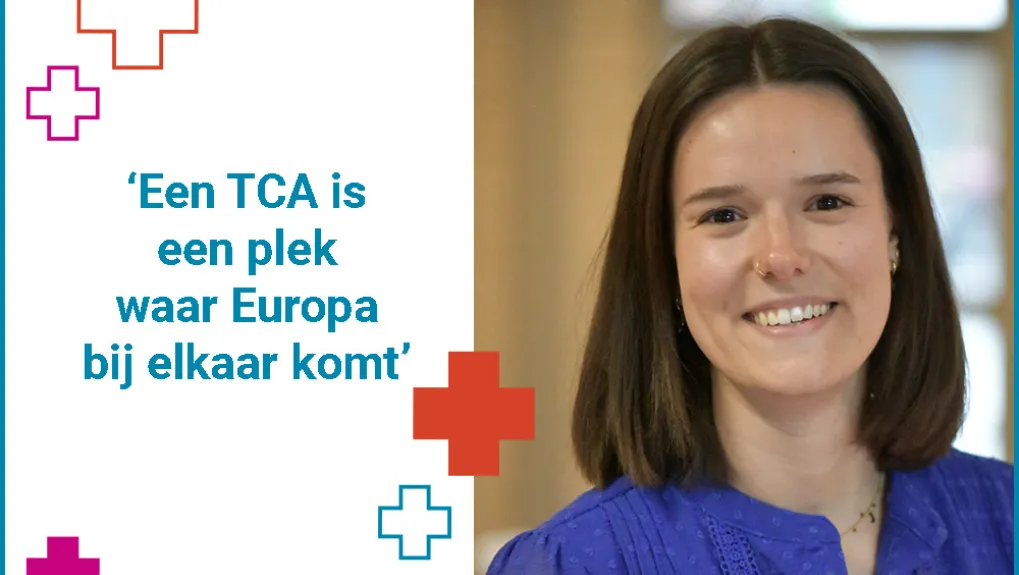Rechterhelft staat een portretfoto van Ruby Maes. Ze heeft stijl donker haar tot op haar schouders en een blouse aan met een diep blauwe kleur. Ze lacht. Links staat een quote: 'Een TCA is een plek waar Europa bij elkaar komt'. De quote wordt omgeven door twee plusjes linksboven en twee plusjes rechtsonder. Rechtsonder is er één plus ingevuld met kleur, de rest is alleen met een gekleurde belijning. 