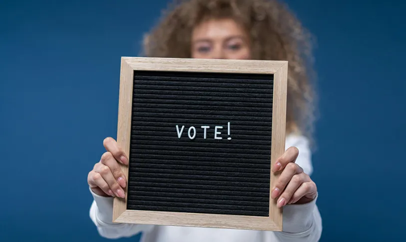 Een vrouw die een bord ophoudt met daarop: Vote!