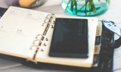 Een opengeslagen papieren agenda plus telefoon op tafel