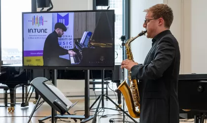 Een saxofonist op de voorgrond, met achter hem op een scherm een pianist. Ze spelen samen een duet, via digitale verbinding