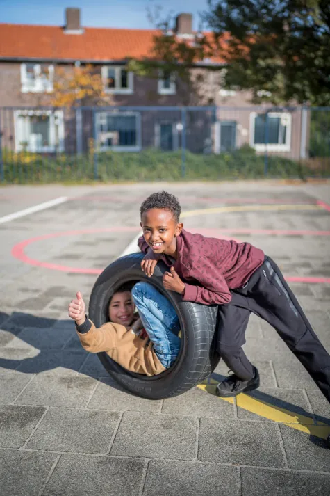 Spelende kinderen in een autoband op een schoolplein